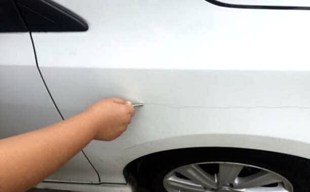 Scratch the car by the keys. Scratch on the car. Bullying scrape the car with anger.