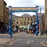 huddersfield, yest yorkshire, United Kingdom - 20 May 2019: the metal outdoor gate of huddersfield open market area and building in byram street with shops stalls and pedestrians